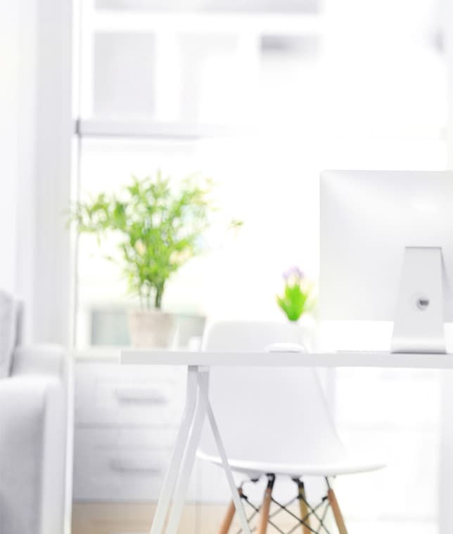 Blurred bright home office corner with a desk, chair, and potted plant